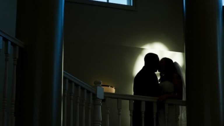 Silhouette of bride and groom, kissing.