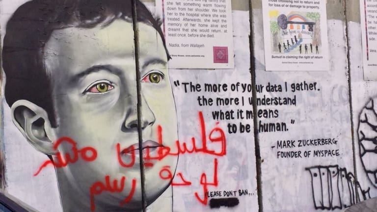 Mural featuring the likeness of Mark Zuckerberg overlaid with graffiti text in Arabic.