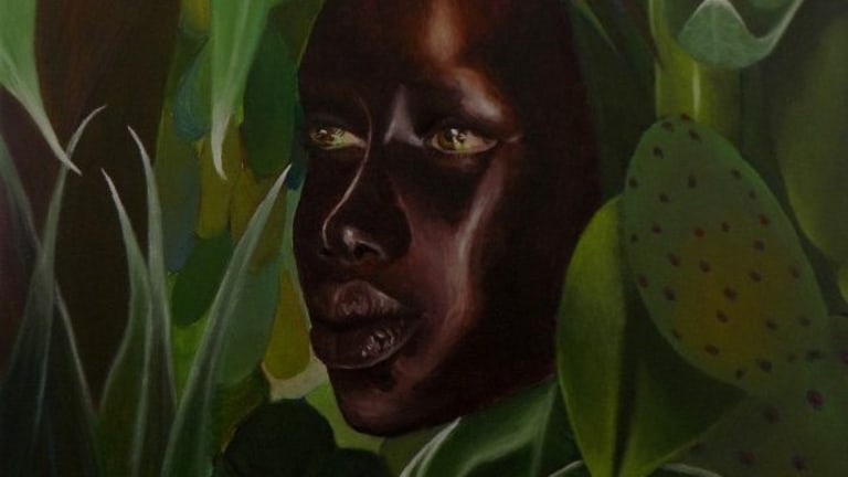 A painting having a face at center and green leaves around it