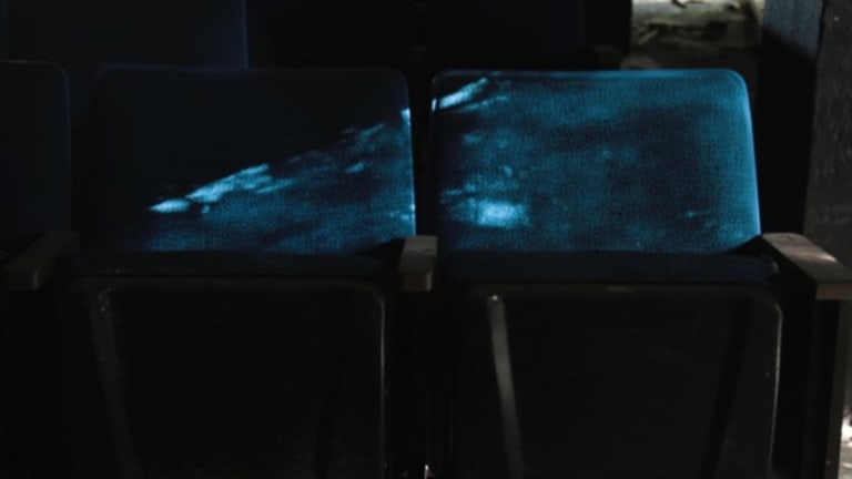 A row of antique folding theater seats covered in blue velvet.