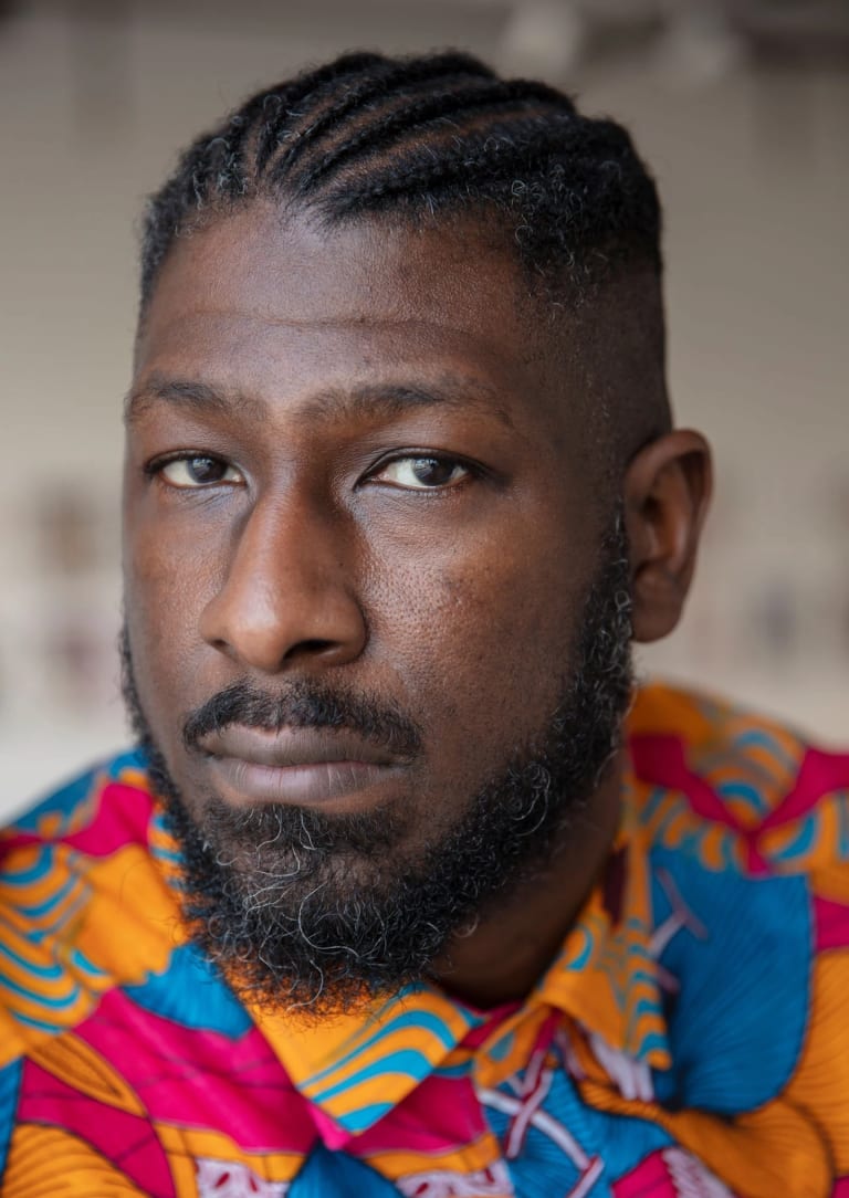 Image of a man looking pensively at the camera with a colorful shirt on 