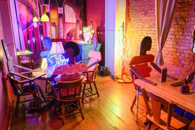 An image of a colorful room, with cardboard people sitting at tables.