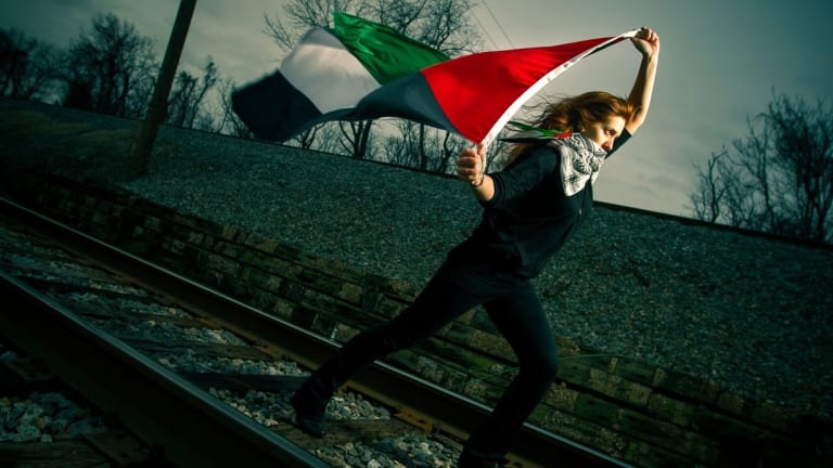 woman running down train tracks with a flag