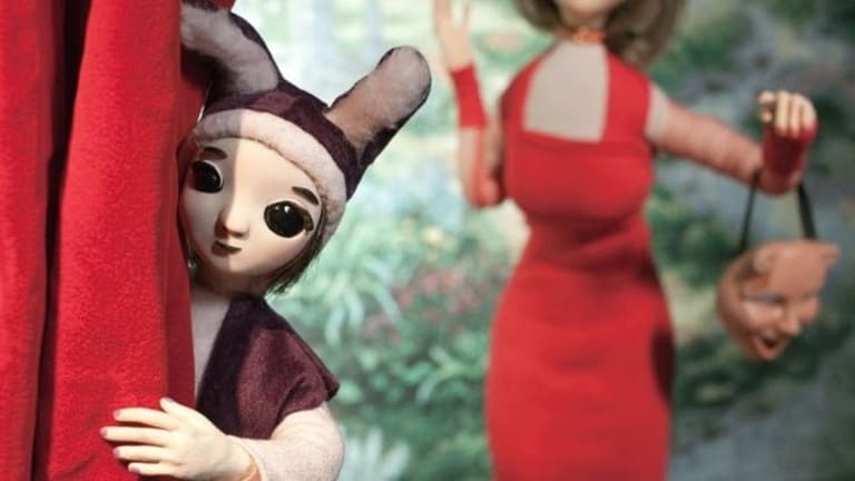 Two lady puppets with one of them wearing a red dress.