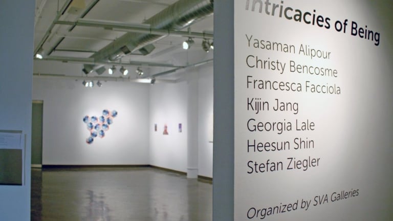A sign listing various artist names on the outside of an art gallery room.