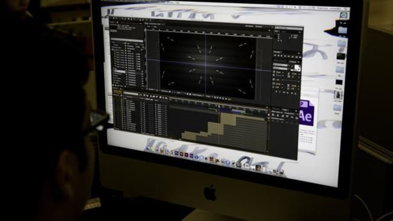 A person using an iMac that is running Adobe After Effects.