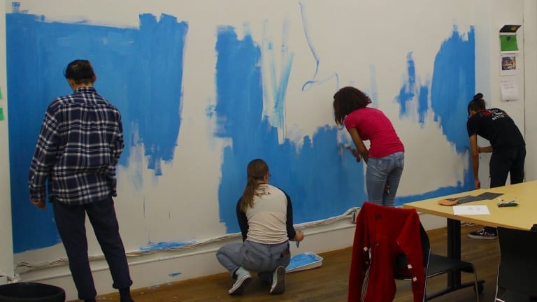 A photo of people painting a wall blue