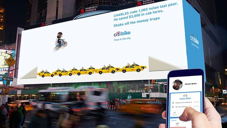 billboard with a citibike ad that has a man on a bike fling over a bunch of cabs