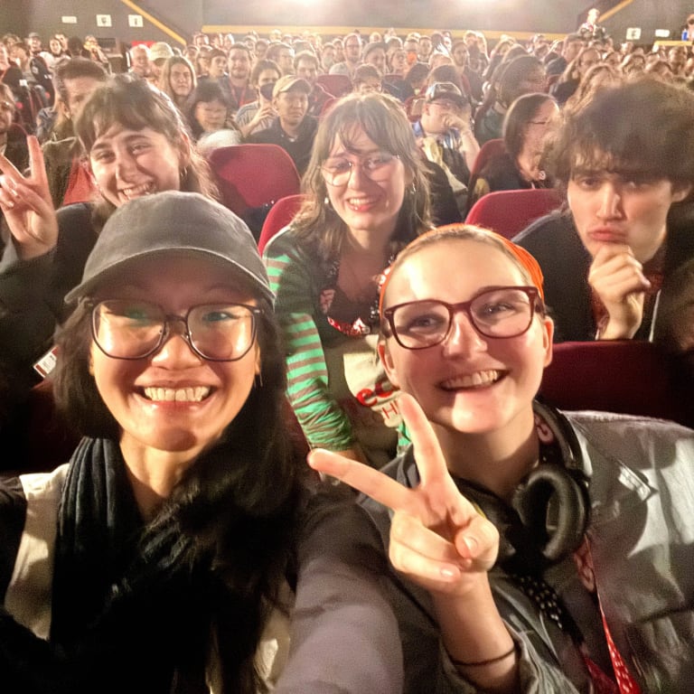 even people smiling while sitting in a movie theater with crowds behind them