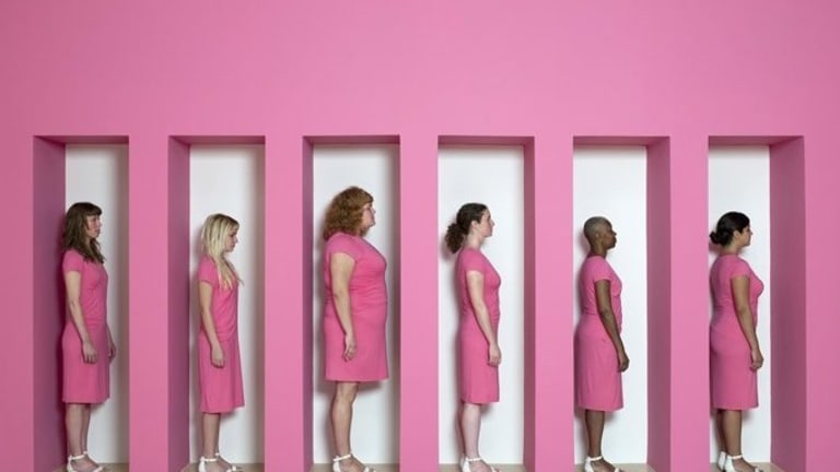 Women of varying sizes and ethnicities stand in profile view wearing pink dresses and white sandals.
