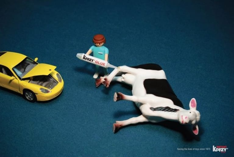 Toy car with hood open and toy figure using Krazy Glue on toy cow.