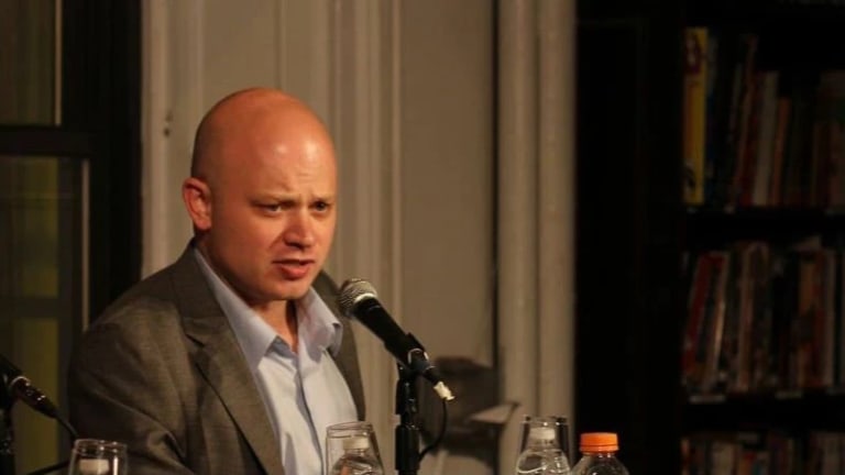 Photo of bald man speaking into microphone