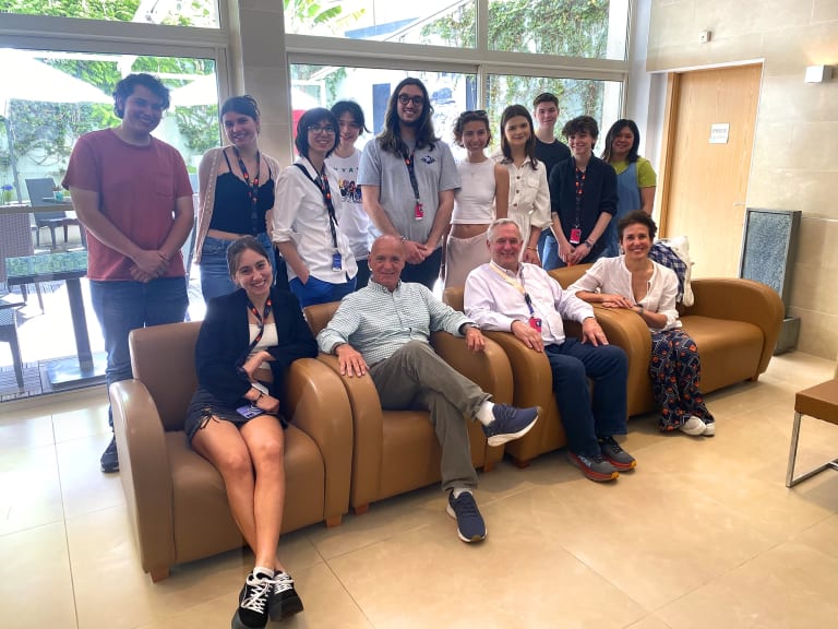 A group of advisors and students sit on a brown sofa posing for a photo at the Cannes Film Festival