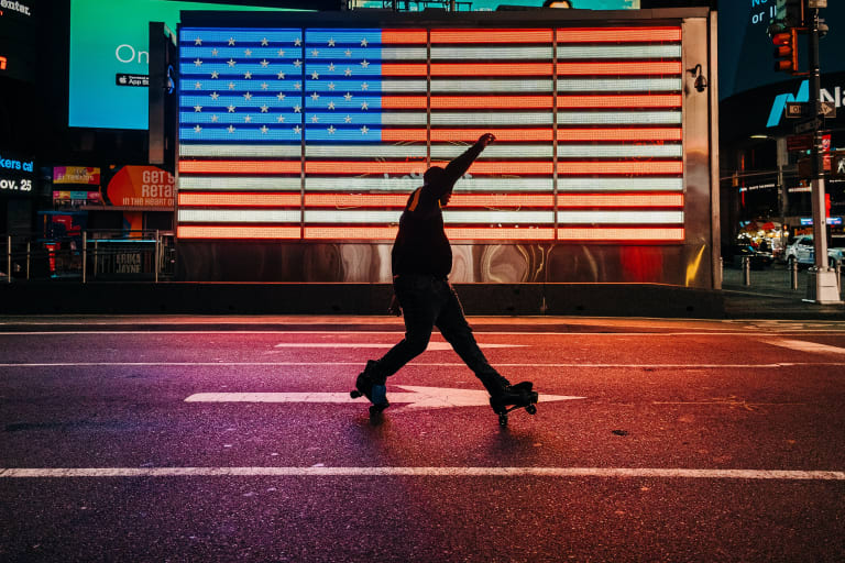 A photograph of a person on roller skates in front of a light display designed to look like the American flag.