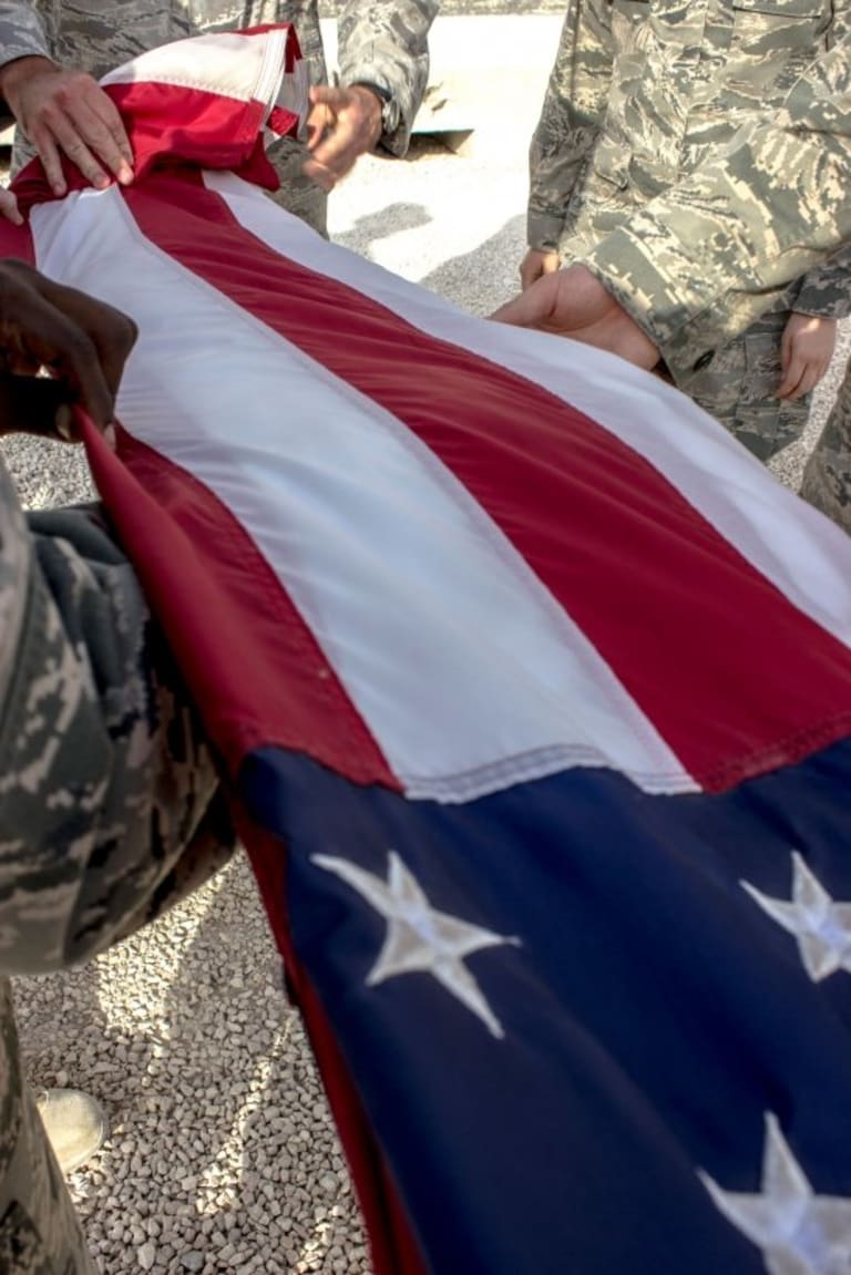 Uniformed individuals holding a folded American flag