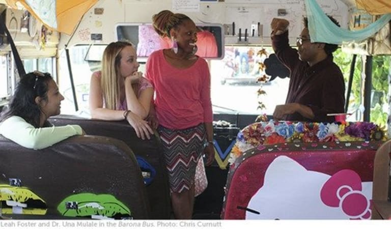 Four adults chatting on a decorated vehicle.