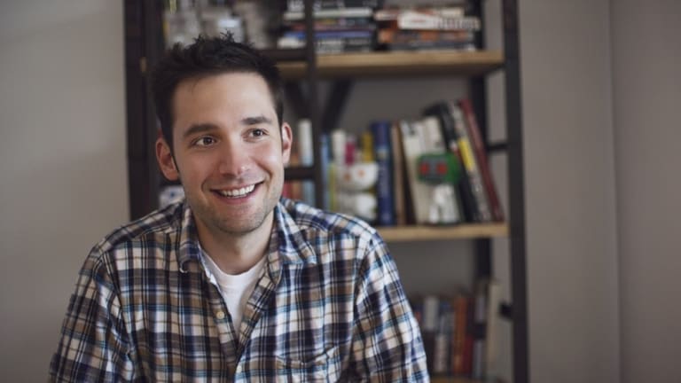 A man smiling for the camera and a book shelf behind him