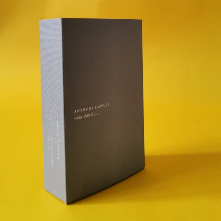 photo of the book dear donald... by artist Anthony Hawley standing against a yellow background