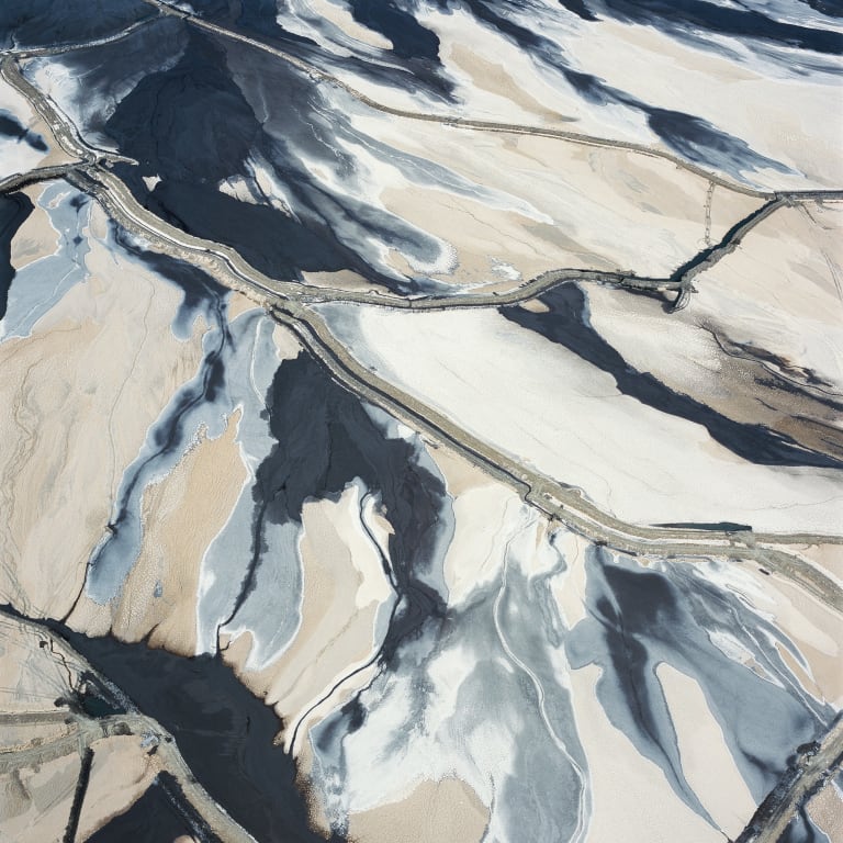 Aerial view of a landscape affected by copper mining looking like an abstract painting in shades of white, gray, black and beige.