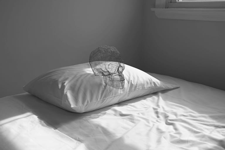 Image of pillow on a bed with a skull on the pillow