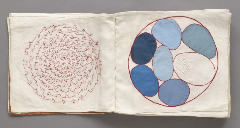 An open fabric book with an abstract embroidered artwork on each page