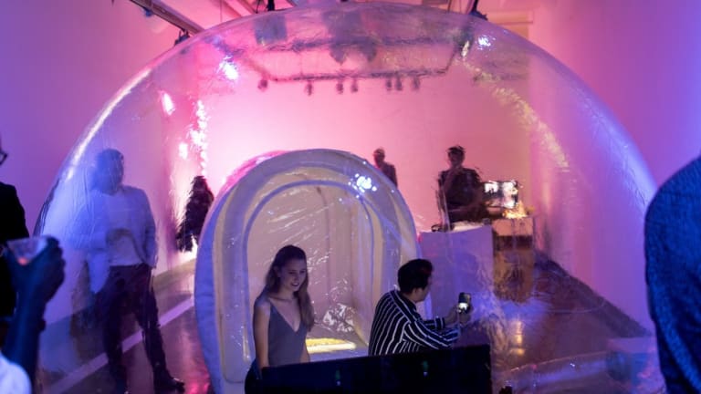 Photo of people an art exhibition with large igloo-like clear plastic bubbles.