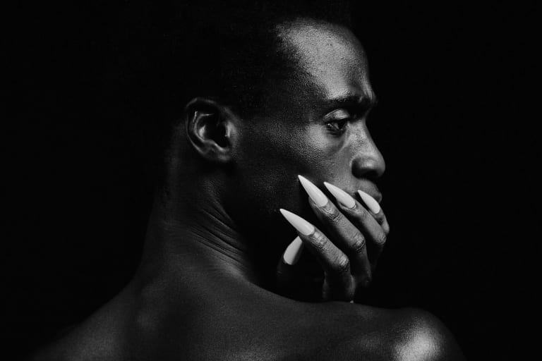 Black and White portrait of man resting styled nails on neck.