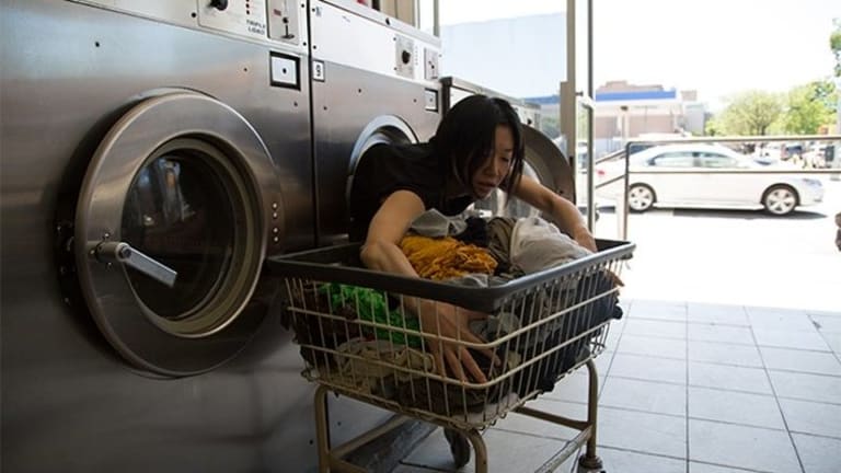 Woman in washing machine reaching for clothes