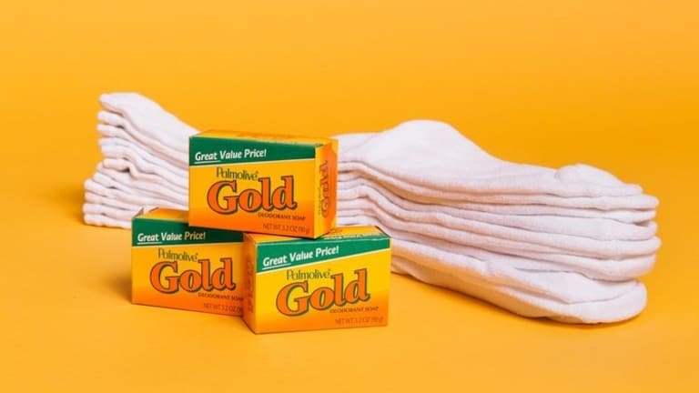 Three packages of Palmolive Gold soap in front of 4 pairs of socks.