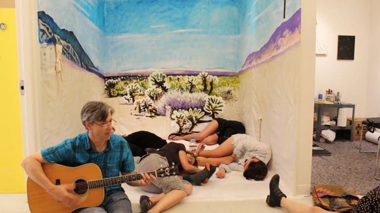 A man playing guitar in front of sleeping people