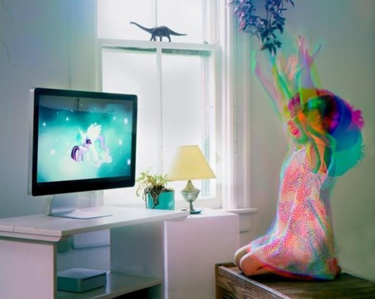 Girl watching a unicorn on her t.v. The girl on the right is moving and smiling.