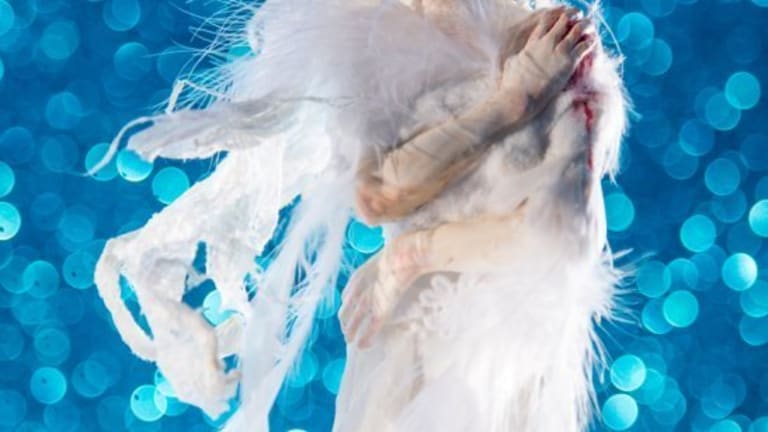 A figurine  in a white angel dress with blood on her hands.