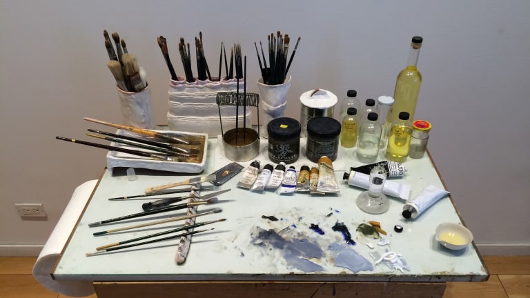 A photograph of paints and paintbrushes.