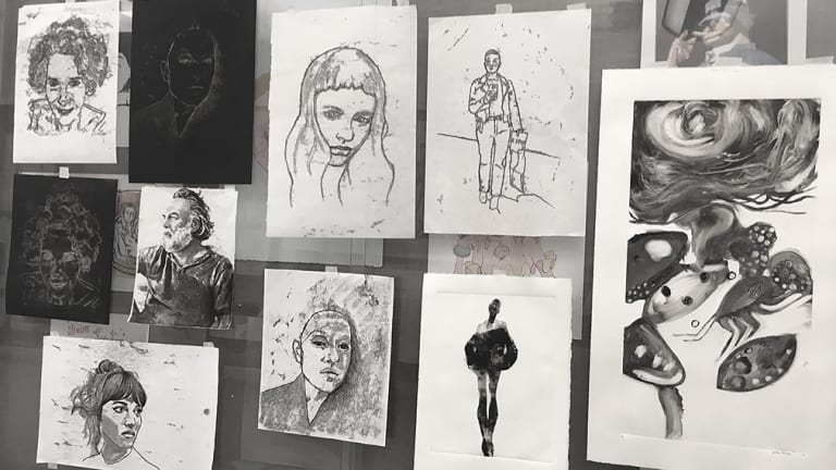 Image of abstract prints and portraits hanging on a wall.