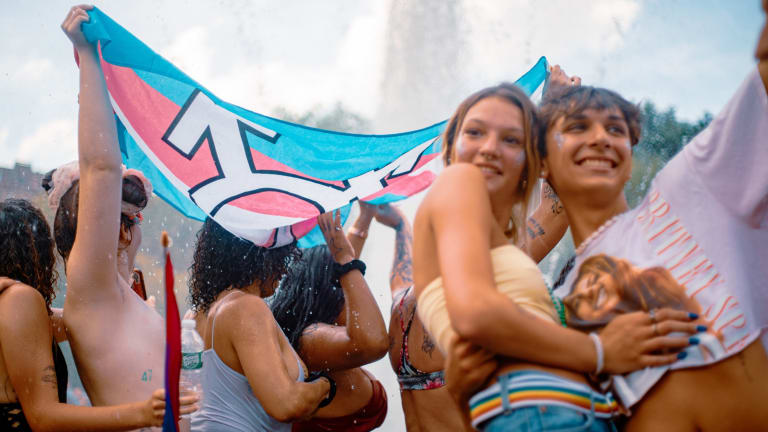 Young revelers at an outdoor rally pose for selfies and wave banners.