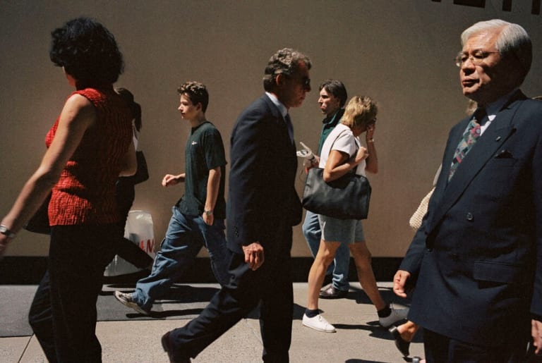 A photo of various people in business attire walking on a sidewalk