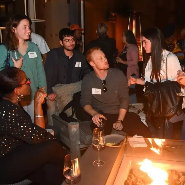 SVA Alumni gather around a fire pit on a rooftop during a gathering.