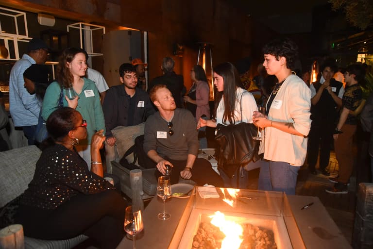 SVA Alumni gather around a fire pit on a rooftop during a gathering.