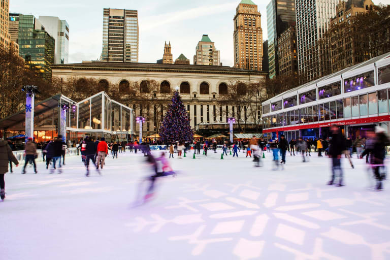 People skate on the Bryant PArk skating rink in front of the New York Public Library