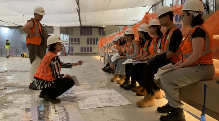 Instructor speaking with students at construction site.