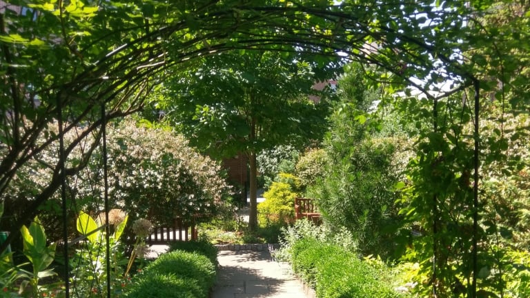 An arch stretches over a pathway leading into one of the gardens at the Church of St. Luke in the Fields.