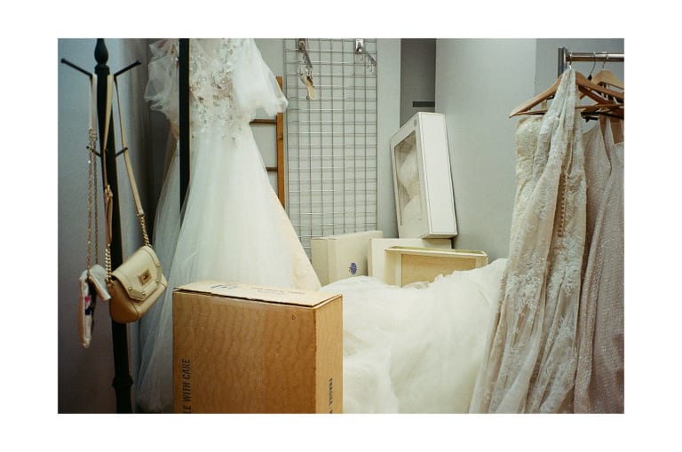 Still from a video by SVA BFA Photography and Video student Geena Janovsky, featuring a dressing room with many wedding gowns hanging and one on the ground.