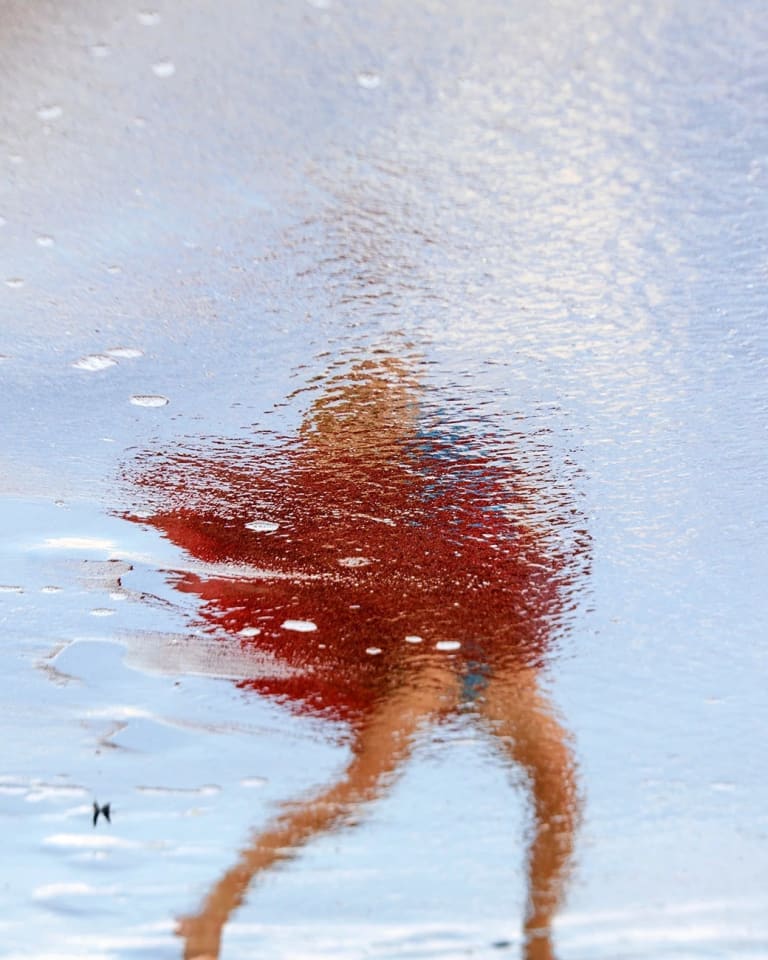 The mood is electric. Shimmering/Floating/Moving dancing red skirt in the process of dissolving above a pair of brown legs that look almost like stick figure that are also in the process of dissolving. It’s all against a light blue background of what seems to be a water of sky/foam/cloud.