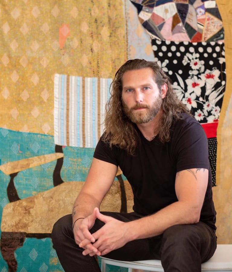 Image of Jesse Krimes in front of textile artwork