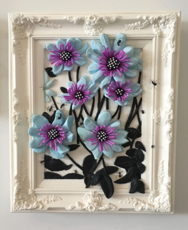 Wall-mounted relief sculpture of light blue flowers with purple stamens emerging from a white baroque frame, with small black insects crawling on the flowers and frame
