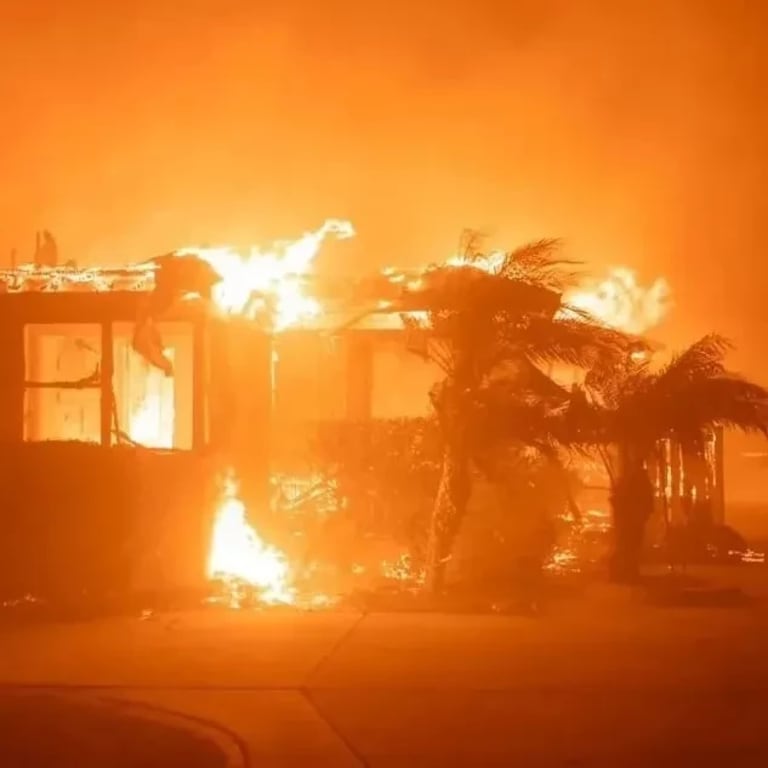 A house ablaze at night, flames consuming the structure, illuminating the dark surroundings with a fiery glow.