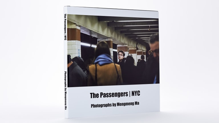 A photo book stands against a white background, with its title "The Passengers | NYC" in black type below a photograph of a person in the subway looking at the viewer.