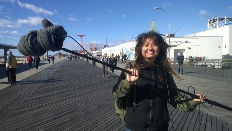 a woman holds a boom microphone on the Coney Island boardwalk