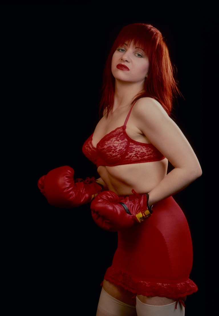 photograph of a woman with red hair in red lingerie, boxing shorts and boxing gloves