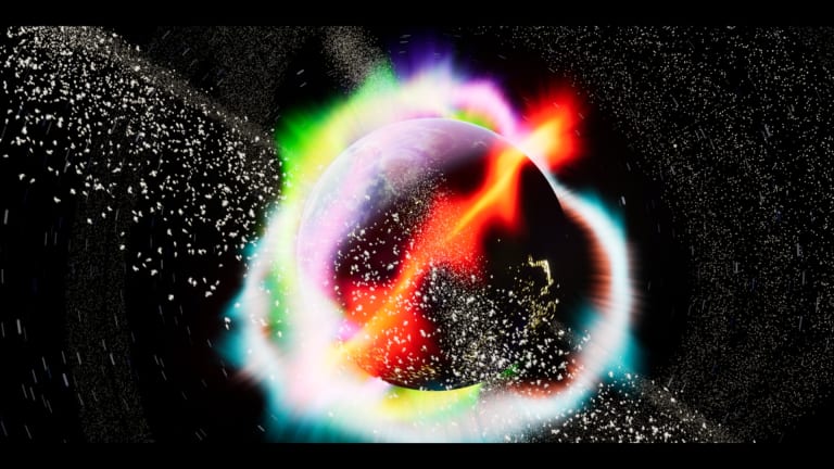 The planet Earth in space is exploding while surrounded by an aura of reds, green, light purple, and light blue, taken from the film Apocalypsis by Emilio Ramos.